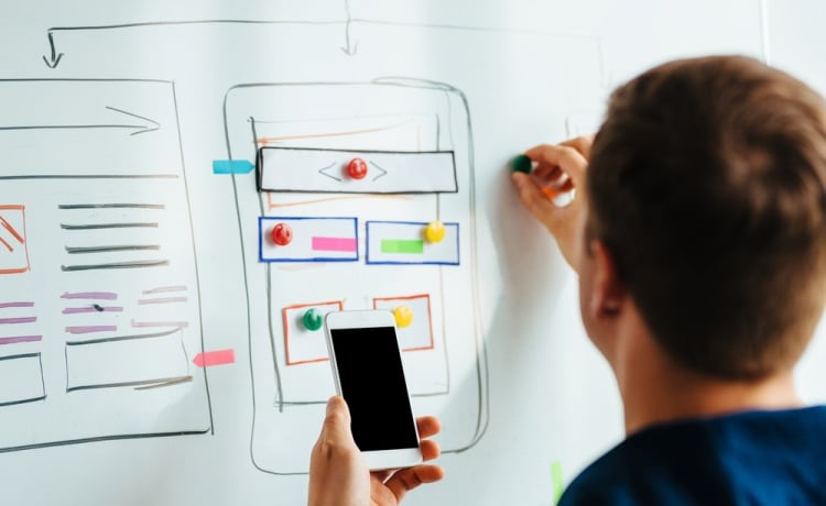 A designer making an app plan on a whiteboard