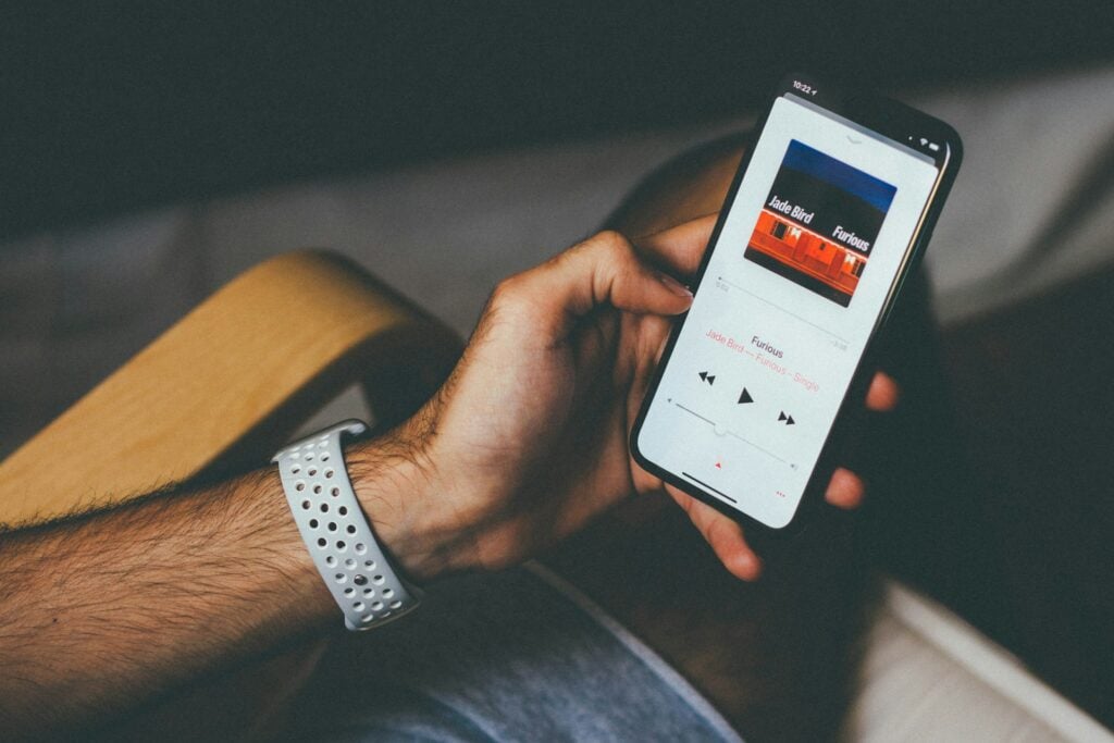 a male's hand is holding a cell phone playing a song 